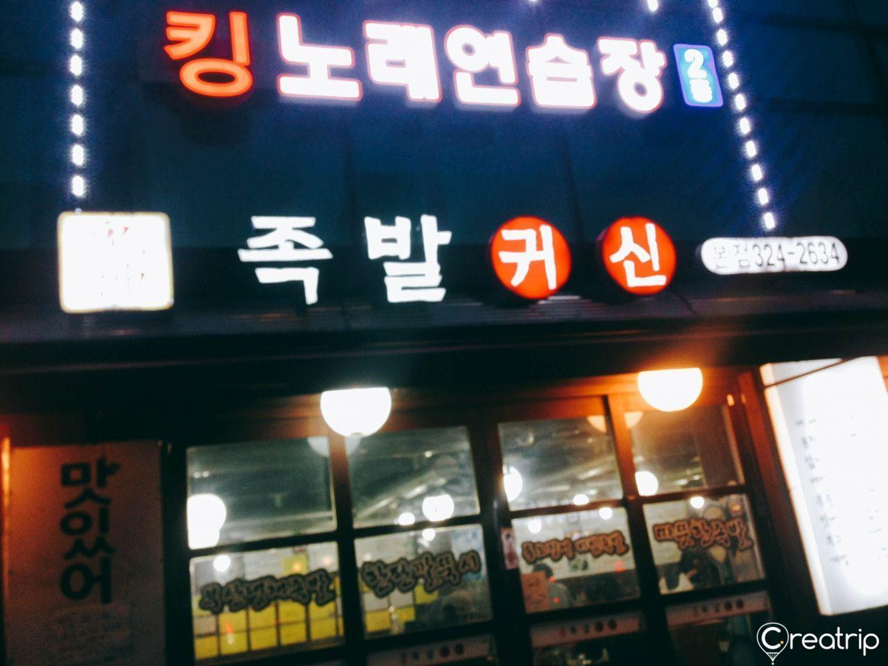 A close-up view of the signboard of Jokbal restaurant '족발귀신', highlighting the restaurant's name and contact number.
