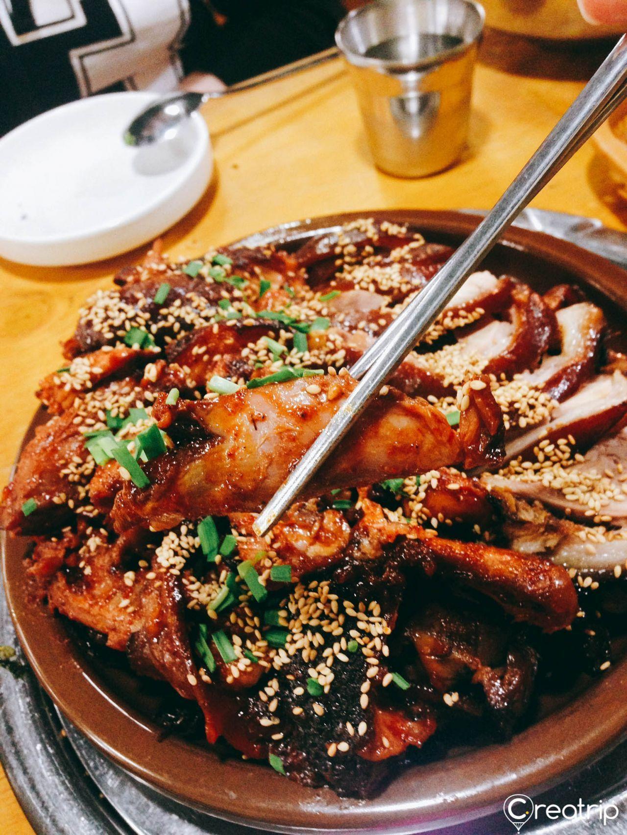 A succulent slice of Korean pork being held with chopsticks, showcasing the dish's savory quality.