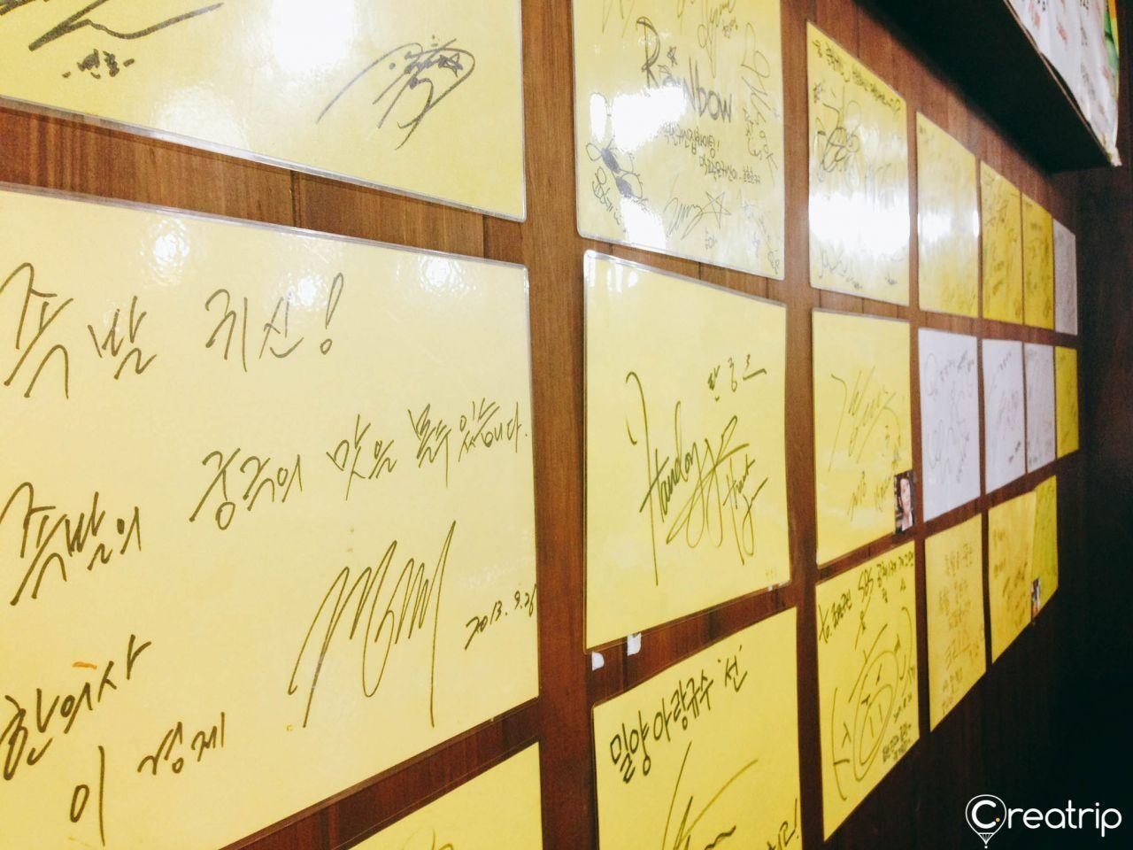A wall filled with celebrity autograph plaques at Jokbal restaurant, indicating the venue's popularity among stars.