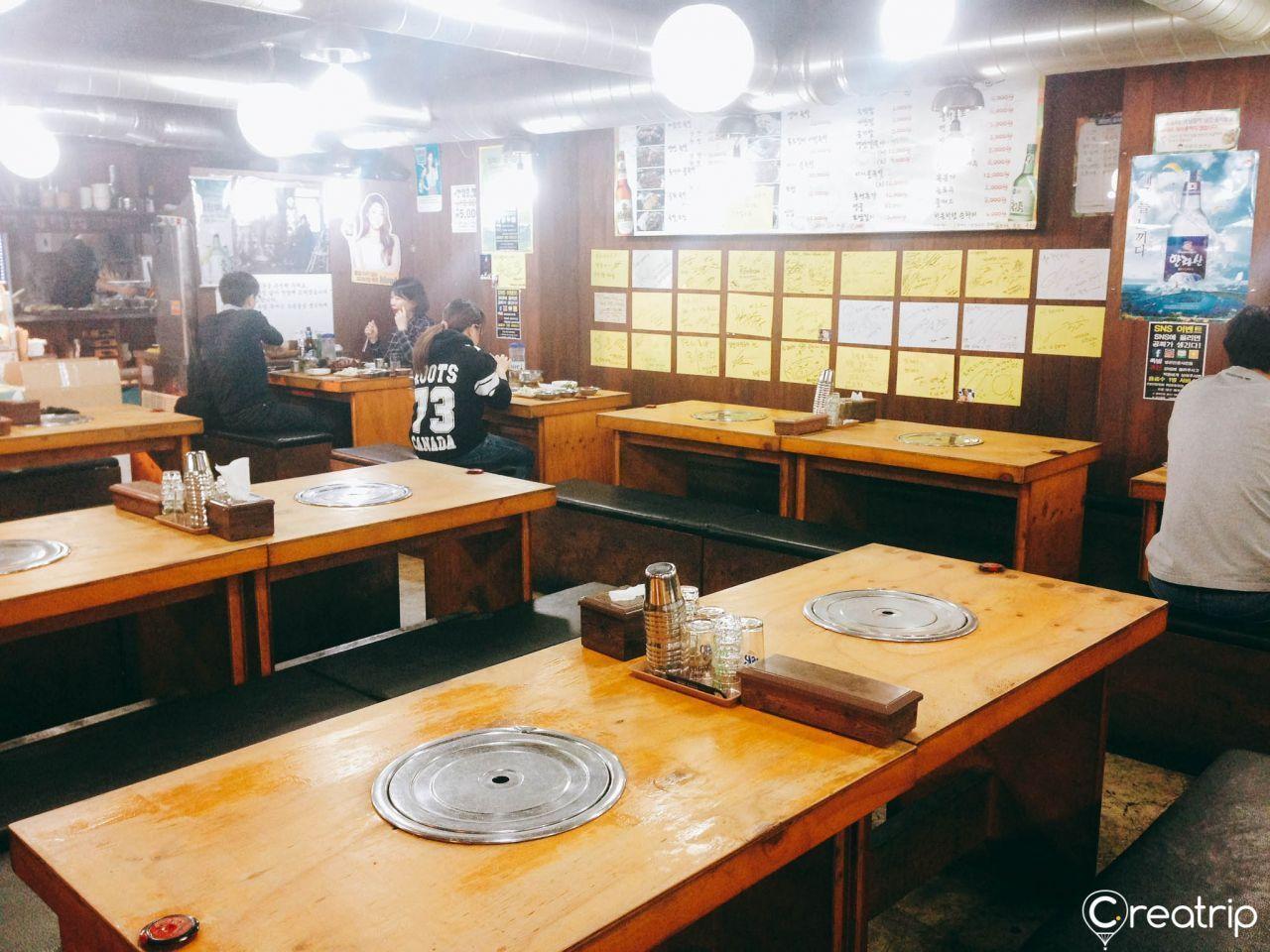 Interior of Jokbal restaurant with traditional wooden tables and celebrity signatures decorating the walls.