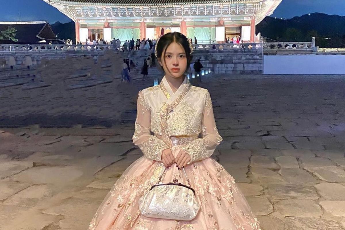 於華麗燈光下站在首爾景福宮外廣場上的穿著粉紅色公主韓服的女性,韓國傳統建築提供優美的背景,完美襯托出公主韓服的華麗細節。