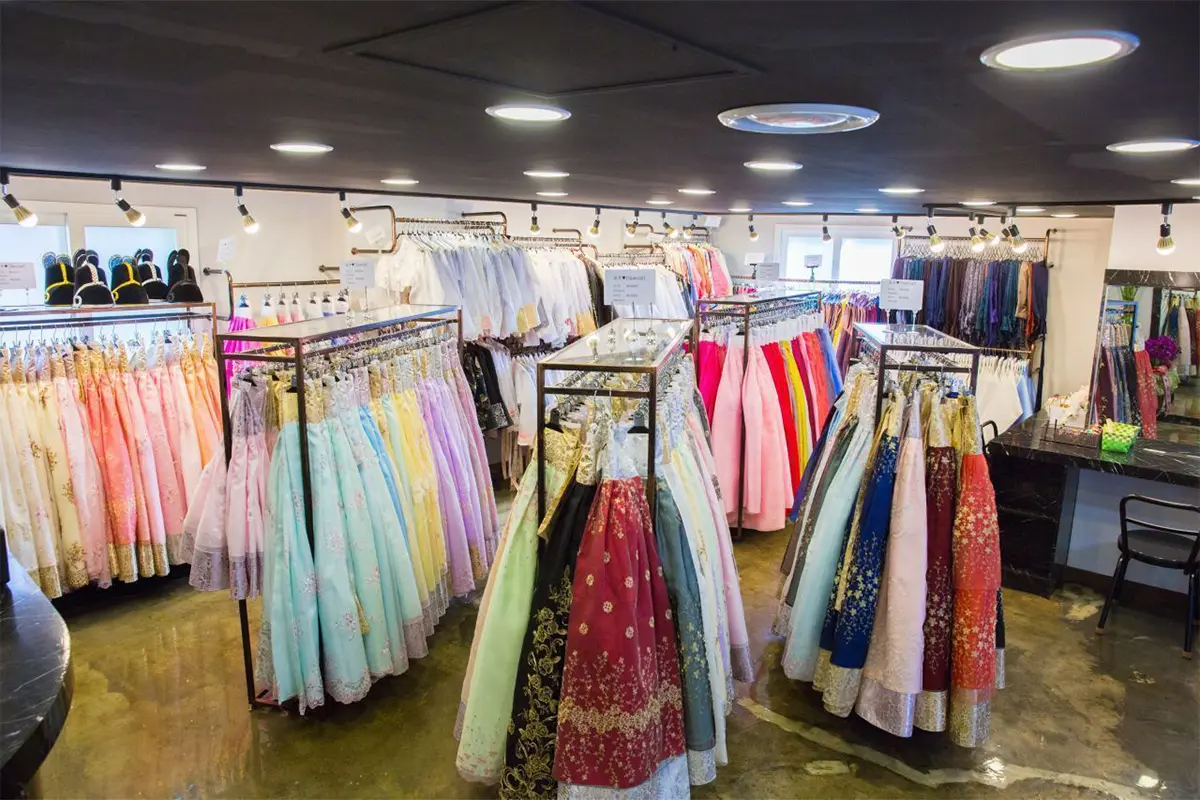 Inside Ohnelharu Hanbok shop, various colorful Hanboks are neatly arranged on racks. The selection includes dresses in pastel and rich colors.