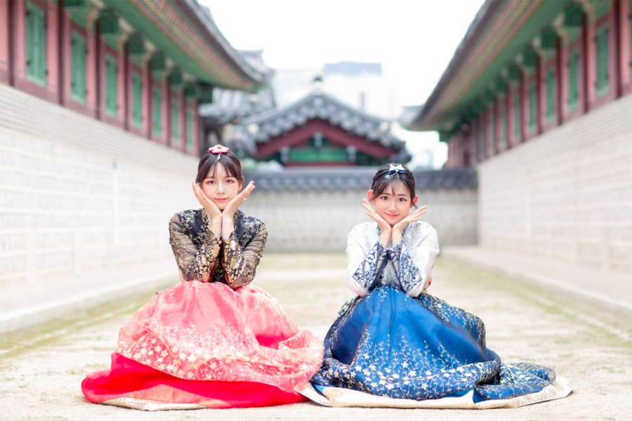 Visitors wearing hanbok seated on stairs at Gyeongbokgung, creating a historical ambiance.