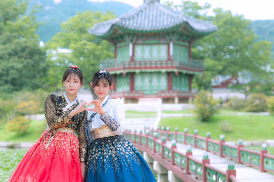Tourists admiring traditional Korean architecture while dressed in elegant hanbok.