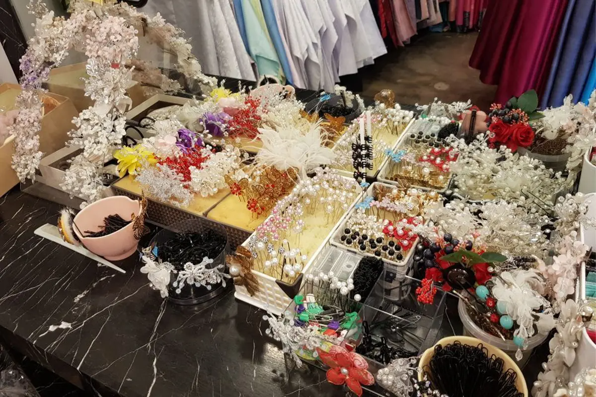 A collection of shiny, colorful hair accessories and flower crowns laid out on a table in Ohnelharu Hanbok shop.