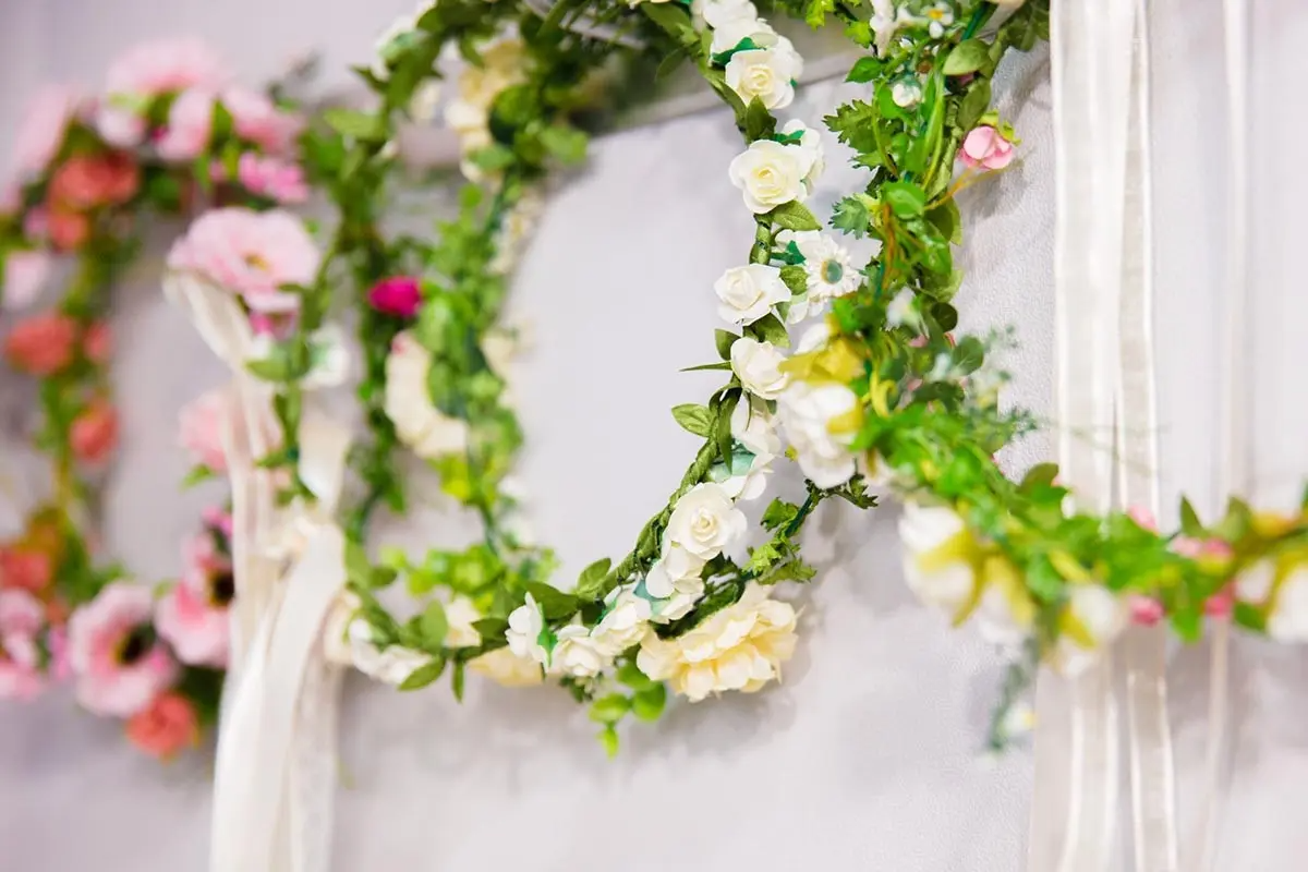 Flower crowns crafted with soft pastel roses and green leaves hanging on display in Ohnelharu Hanbok shop.