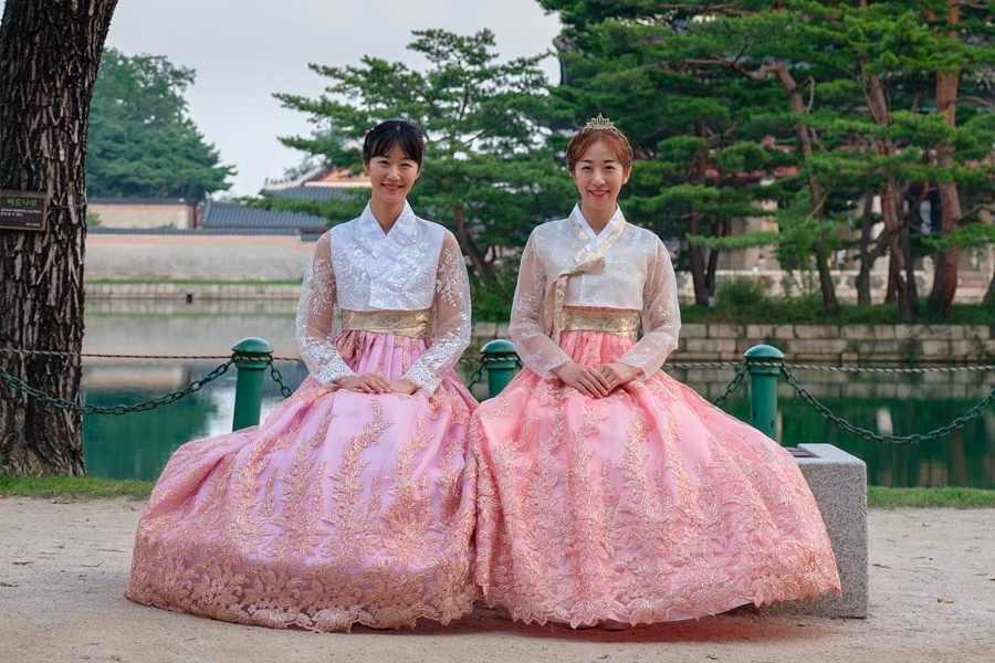 Tourists clad in hanbok, engaging with traditional Korean settings and architecture.