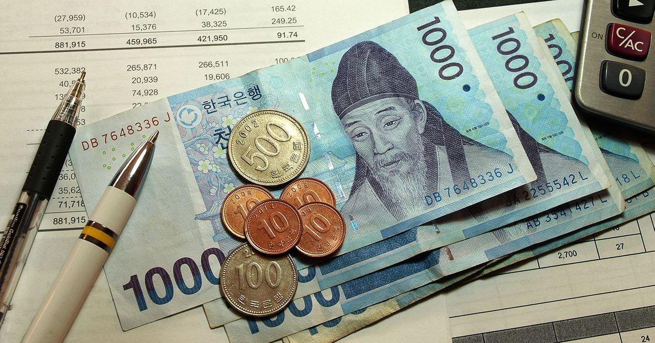 South Korean currency notes and coins arranged on a table with pens.