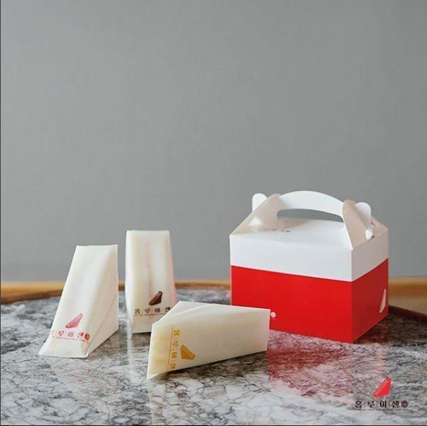 Box of HUNG RUI CHEN sandwiches elegantly displayed on a marble surface.