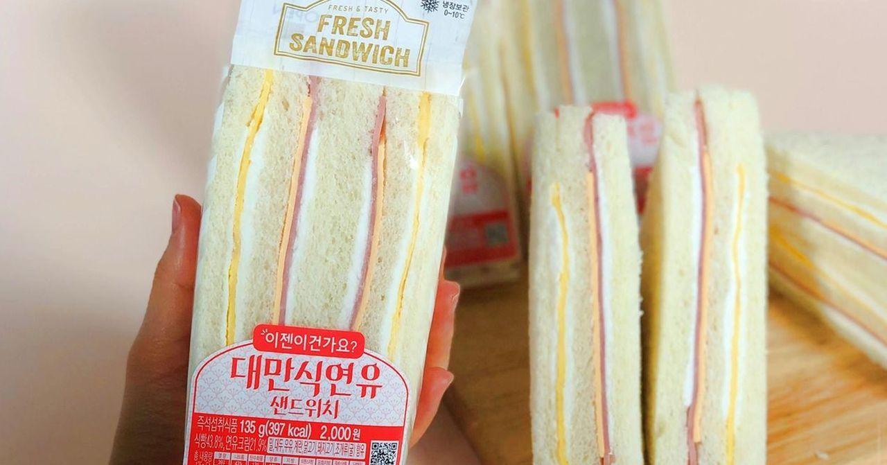 Close-up of Taiwanese-style fresh sandwich packaging held by a hand.