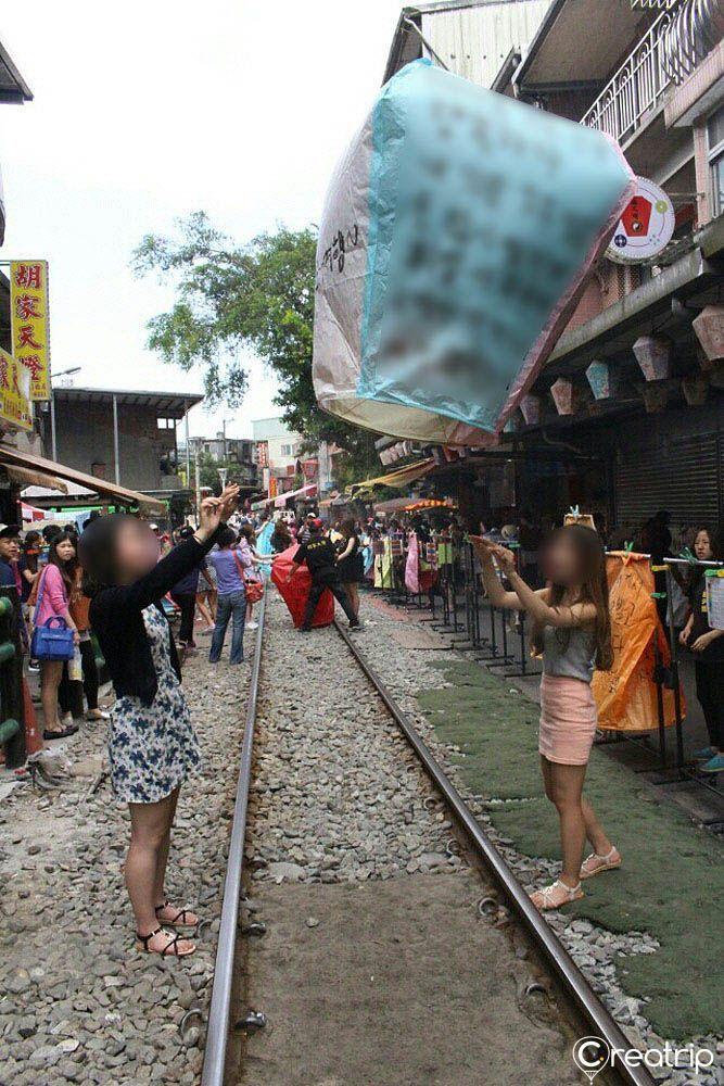 Tourists at Pingxi releasing a sky lantern, an iconic experience in Taiwan where wishes are written on lanterns before sending them up into the sky.