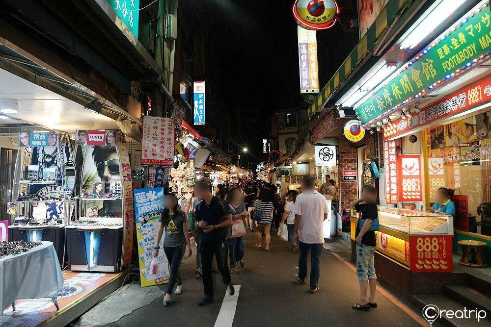 Bustling street inside Shilin Night Market, crowded with visitors exploring various vendors and shops at night in Taipei, Taiwan.