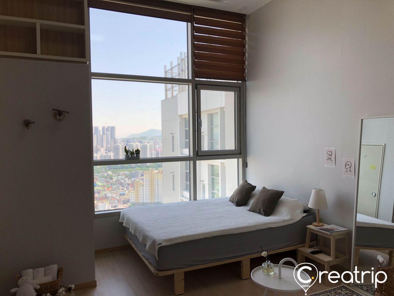高層公寓的寬敞卧室，從大窗户可以看到韓國大邱的城市景觀。