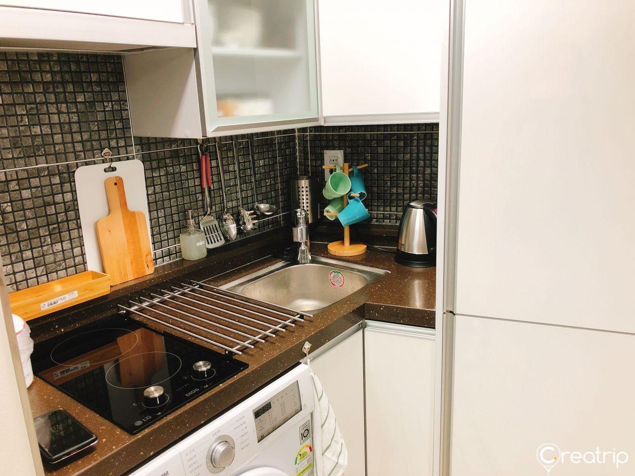 小型工整的廚房，配有電磁爐、洗衣機，以及其他基本廚房設備。