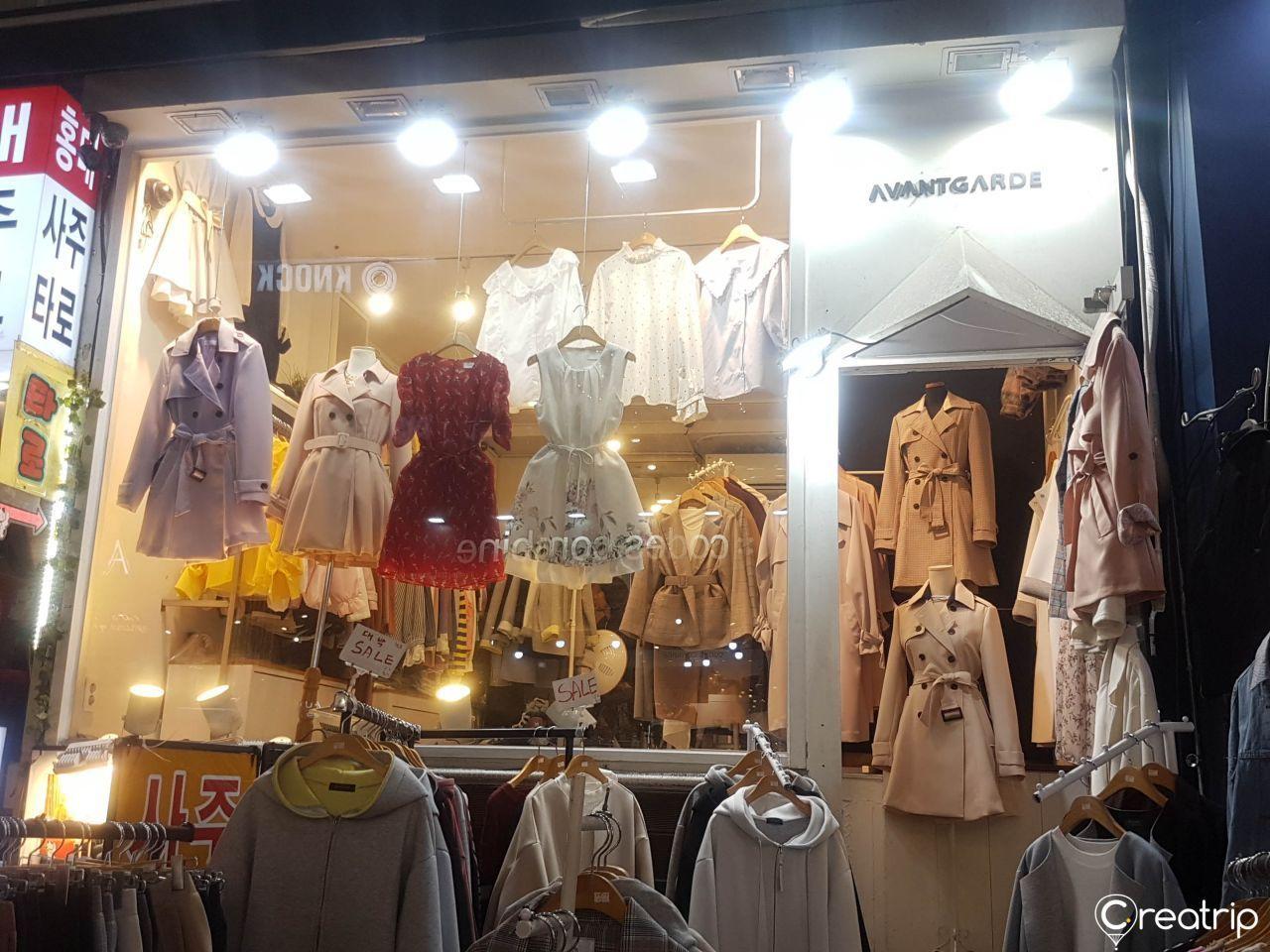 弘大时尚商店，橱窗中展示着多款韩国女性服饰，吸引大量购物者驻足。