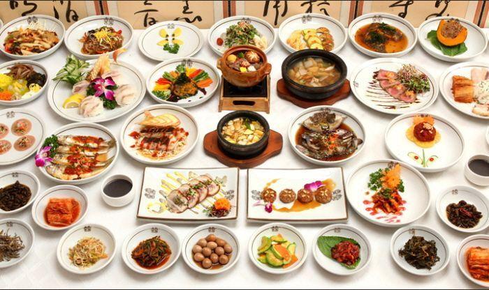 韩国传统美食摆放在餐桌上，包括多道小菜和热汤，展示丰富的韩餐料理文化。