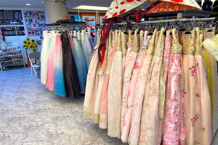 Clothing rack filled with colorful hanboks arranged in a vibrant store setting.