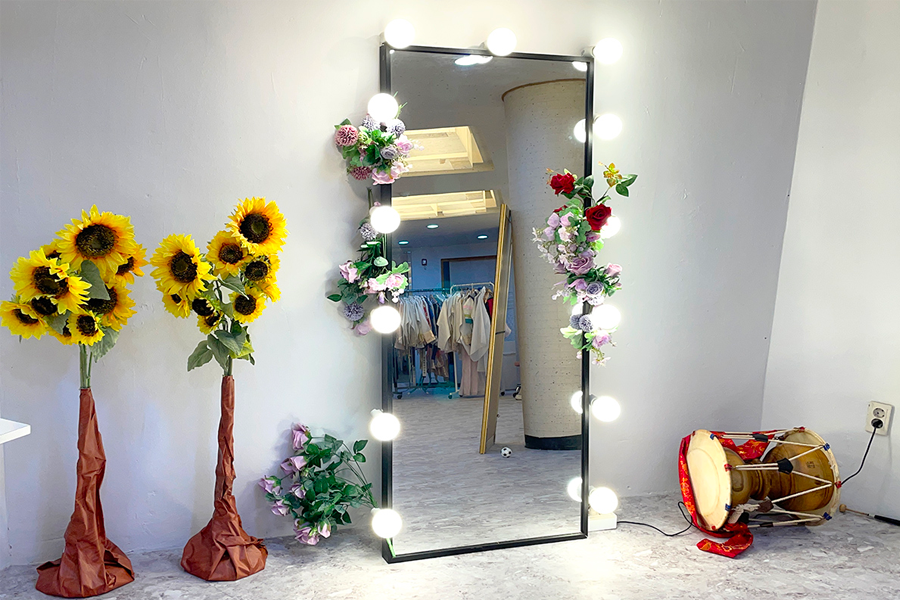 Mirror decorated with flowers in a store offering hanbok rentals and styling services.