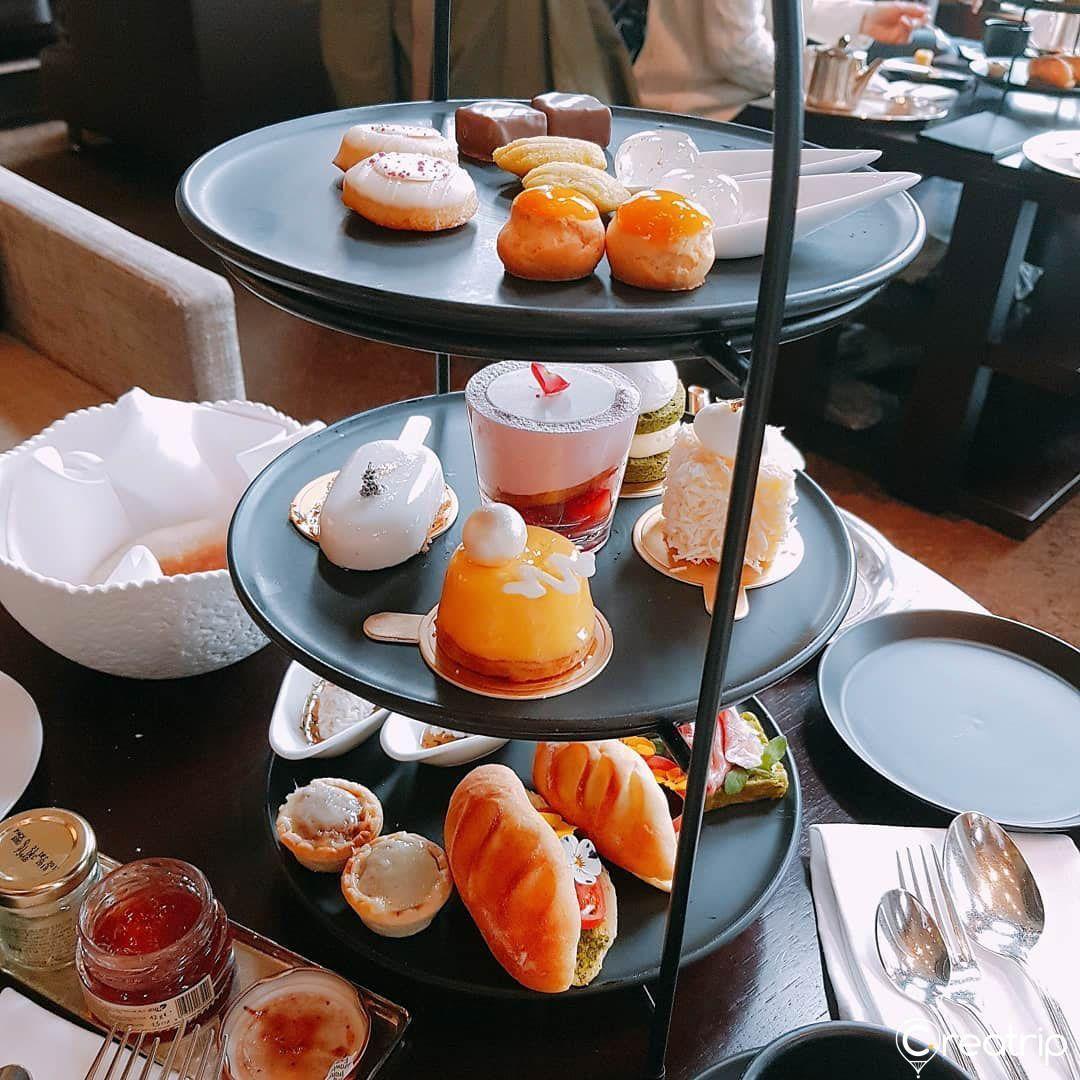 Elegant presentation of Korean afternoon tea set with sandwiches, scones, cakes, and macarons on a multi-tiered stand, inspired by Heart Signal show.