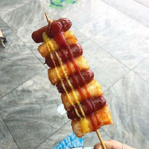 Photo of Korean street food called '串香腸年糕', featuring skewered sausage and rice cakes with sauces, popularized by celebrity Lee Young-ja.