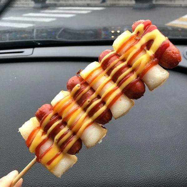 Image of Korean '串香腸年糕', showcasing delicious sausage and rice cake on a stick, highlighted by ketchup and mustard toppings.