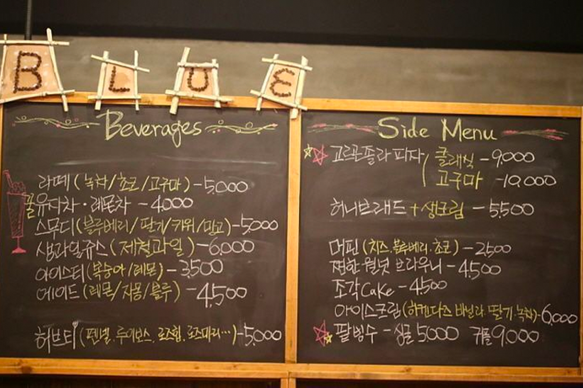 黑板上用韓文寫的飲料和小吃菜單，標題是 BLUE BEVERAGES，包含多種飲料選擇和價格。