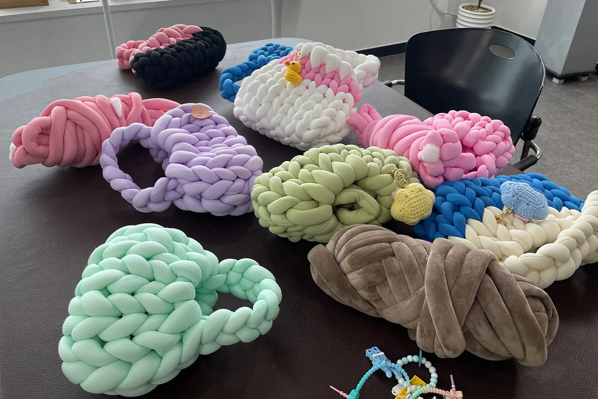 Collection of handmade knitted bags using chunky yarns showcased at Korean DIY workshop, demonstrating creativity and comfort.