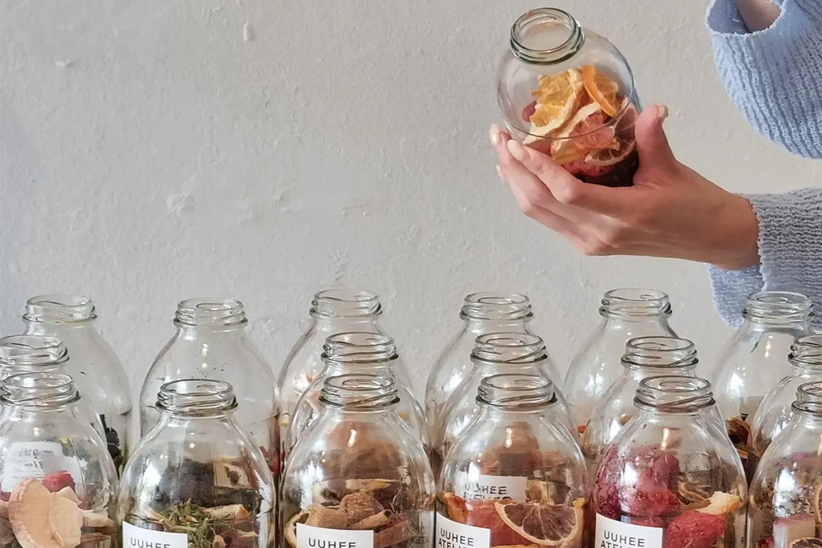 一位參與者在UUHEE Atelier DIY體驗館中，將乾燥水果放入玻璃瓶中，用於製作手工酒。