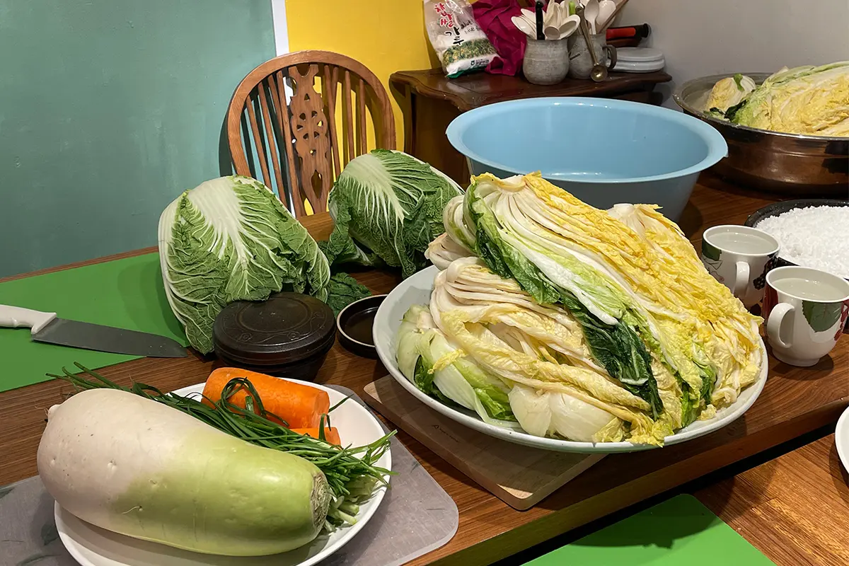 Fresh ingredients for DIY kimchi workshop in Korea, featuring traditional Asian vegetables and spices on a wooden table.