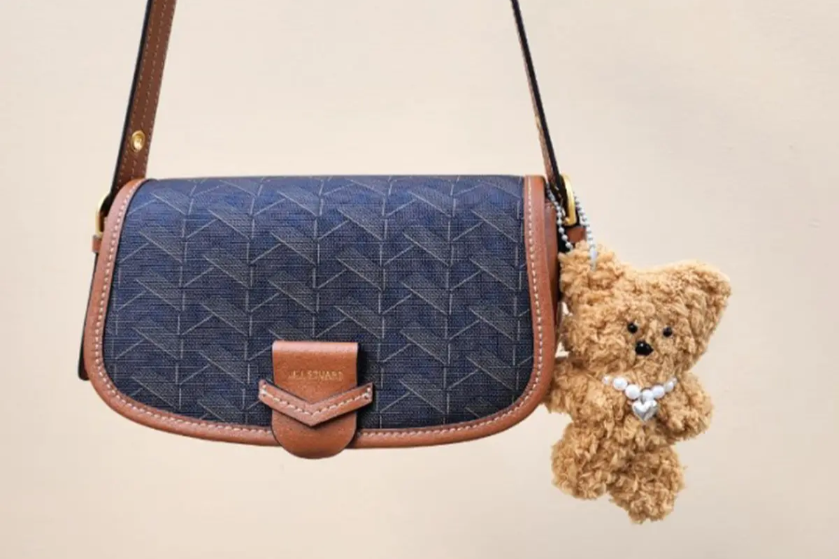 一個韓國手工製作的毛毛公仔掛於精緻皮包上，展示出精湛的工藝與設計感。