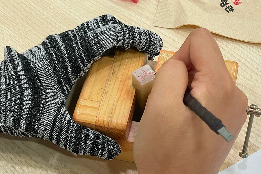 Detailed carving of a Korean stamp block in a DIY workshop, emphasizing traditional skills and craftsmanship.