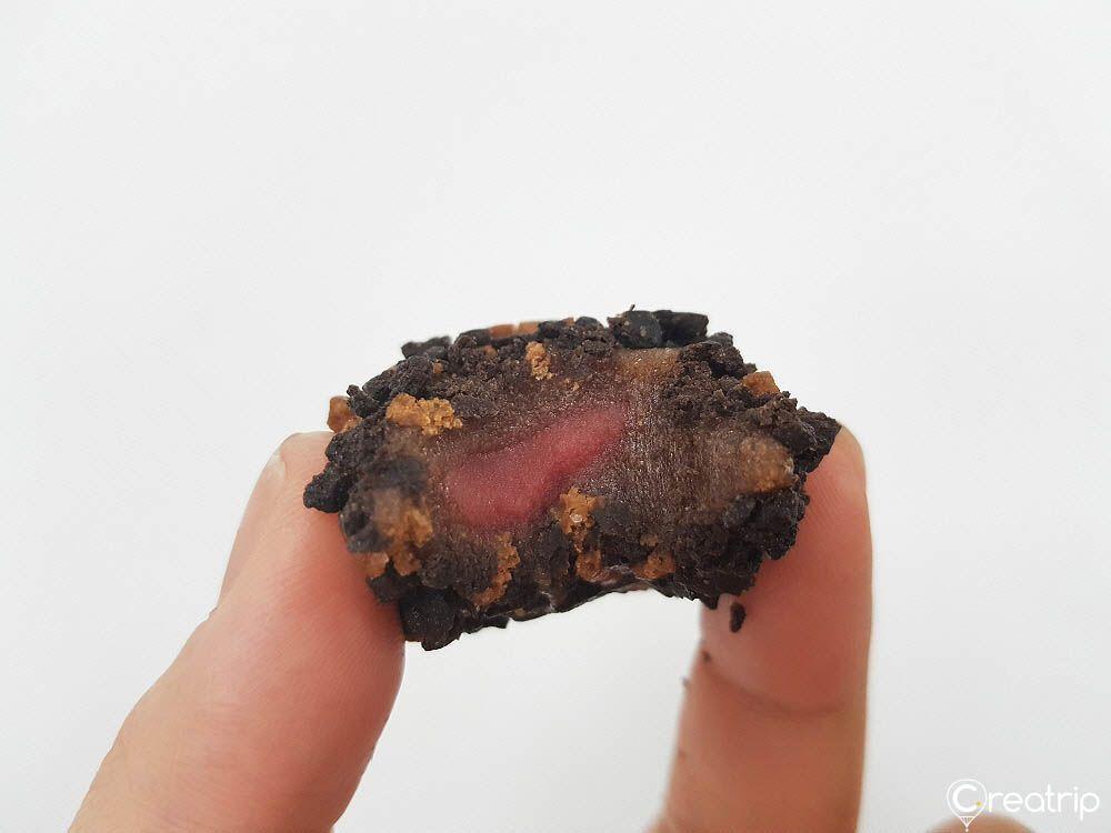 A bitten strawberry chocolate rice cake ball showing chewy texture and filling