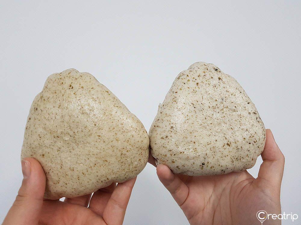 Two triangular-shaped breads, often mistaken as rice balls, in hand