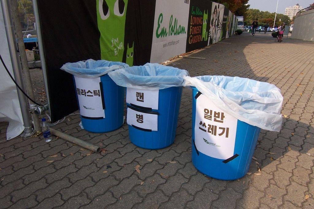 三个蓝色垃圾桶，标有不同类型的废品分类。