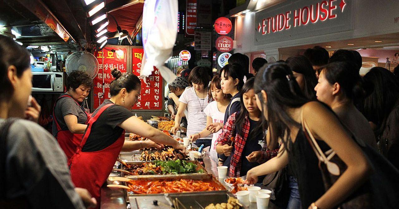 一条拥挤的韩国街道，一家小吃摊上围满了人。