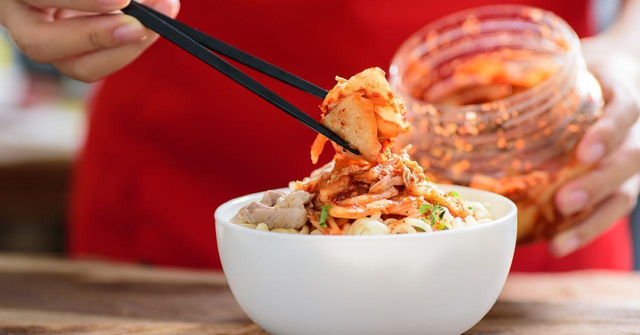 用筷子夹起泡菜放入碗中，是韩国日常饮食的一部分。