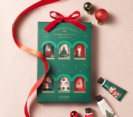 Coffret cadeau de Noël Innisfree avec crèmes pour les mains parfumées, décoré d'ornements festifs.