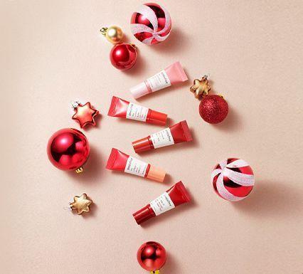 Produits de beauté Noël Innisfree avec des teintes rouges et des décorations métalliques, évoquant l'esprit des fêtes.