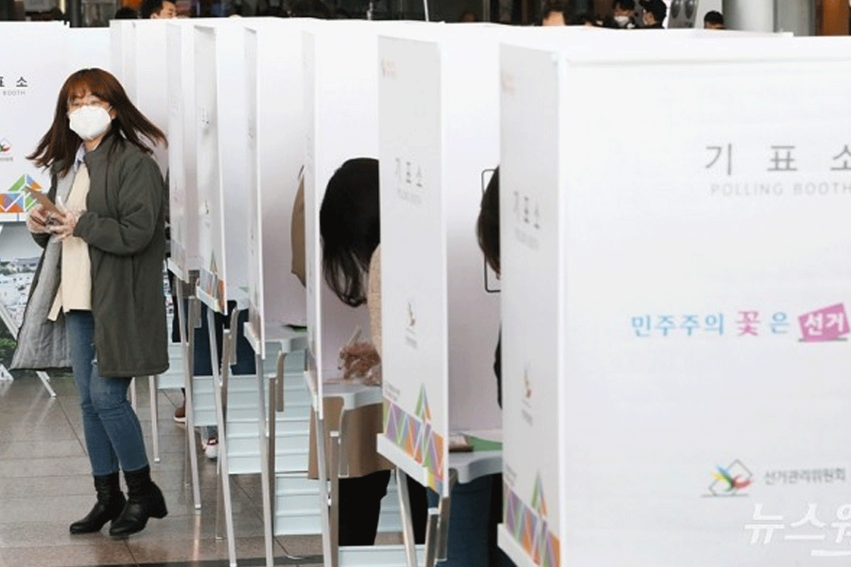 A woman voting inside a polling booth during South Korean elections, highlighting the country's commitment to democratic processes.