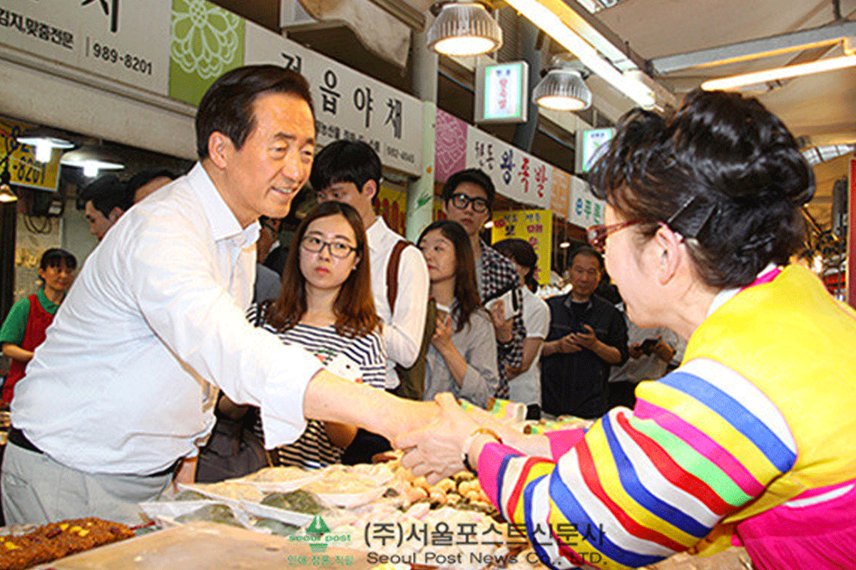 South Korean political candidate engaging with citizens at a local market, depicting grassroots campaigning in action.