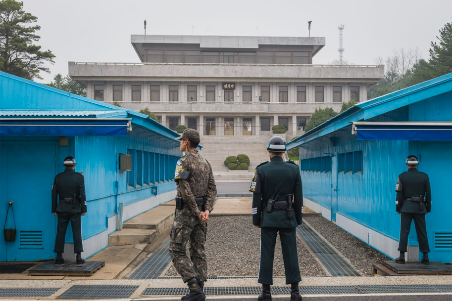 Military personnel stationed at the Korean Demilitarized Zone, illustrating the divide between North and South Korea with blue UN buildings in view.