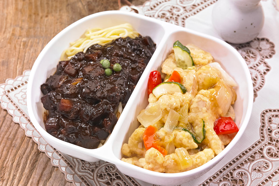 半份糖醋肉加半份炸醬麵，擺放在雙格餐盒中，既能享受酥脆的糖醋肉，又能品味沉浸在濃鬱黑色醬汁中的炸醬麵，多重美味的一餐。