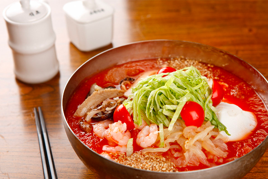 一碗韓式冷海鮮麵，裡面充滿新鮮的海鮮和蔬菜，覆蓋紅潤辣味湯底，清涼且刺激的口感，是適合夏日享用的開胃美食。