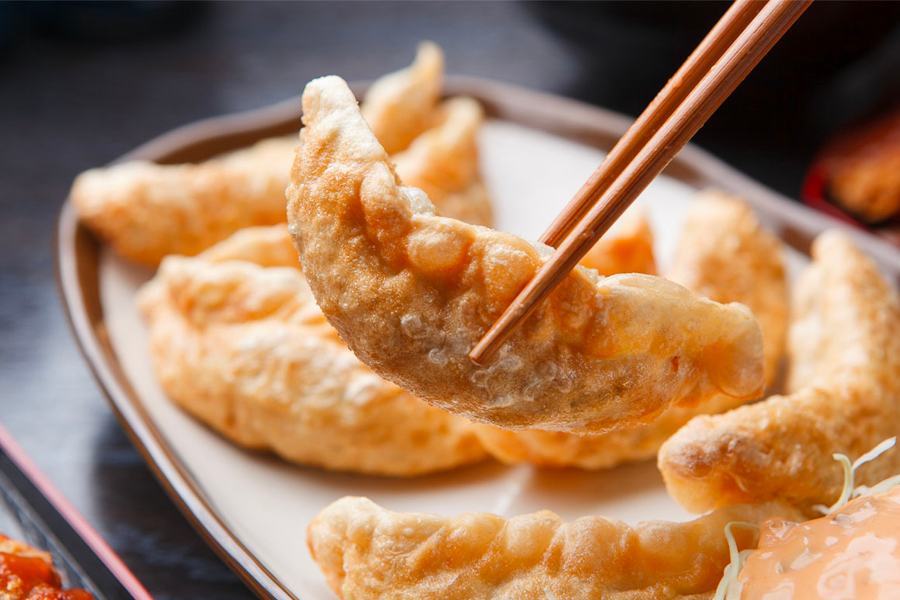 韓式炸餃子，金黃酥脆的外觀讓人食指大動，擺在淺色的盤子裡，視覺上烘托出其美味的內餡，可作為完美的小吃和主餐搭配。