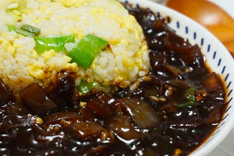 一份中華炸醬炒飯，稻米上有黑色的炸醬和豐富的蔬菜，顯示出中韓風味結合的獨特美食，適量濃鬱的醬汁讓舌尖感受到壓倒性的美味。