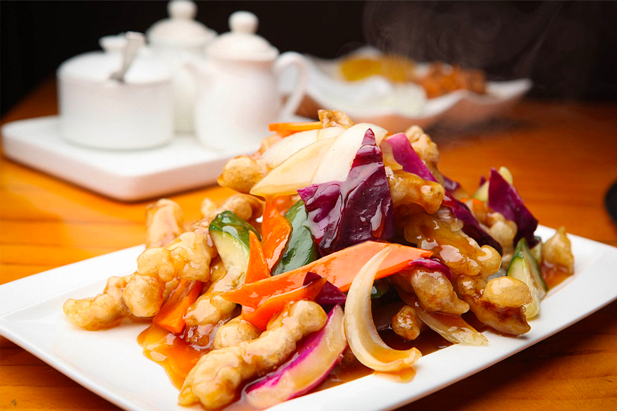 一盤韓式糖醋肉，呈現金黃酥脆的牛肉條，搭配多汁的糖醋醬和新鮮的彩椒片，色彩繽紛且誘人，激發出豐富的品味和口感體驗。