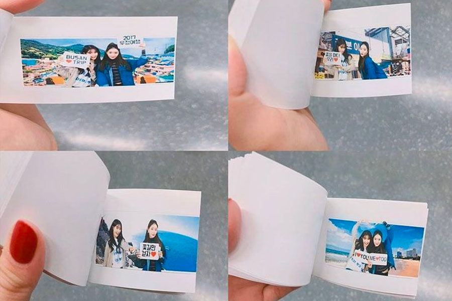 한 손으로 들고 있는 다양한 고객의 사진 콜라주가 그려진 소형 포토북. 부산의 다양한 관광지 배경이 포함된 장면들이 담겨 있다.