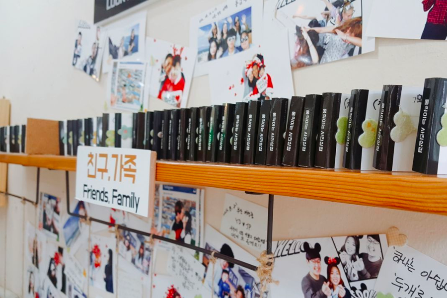 움직이는 사진 상점 내부의 선반에 진열된 책과 가족 사진들. 다양한 스타일의 포토북이 친구, 가족, 커플 섹션에 나눠져 있다.