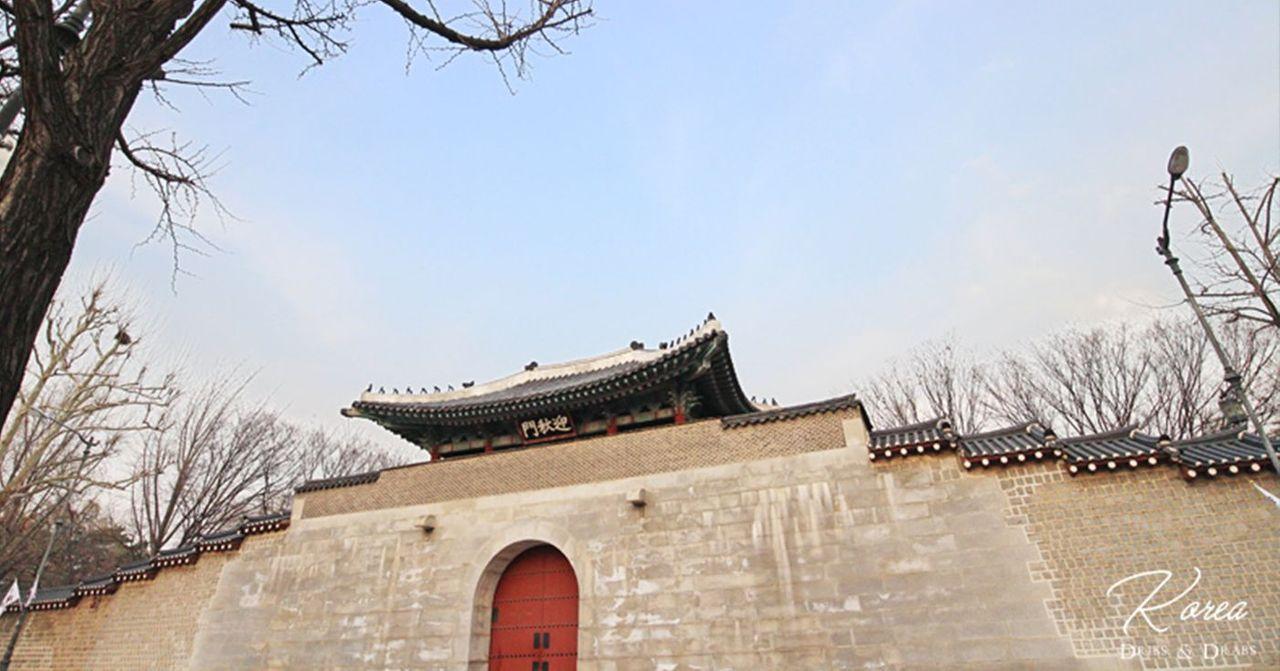 경복궁의 성벽과 나무의 이미지, 겨울철 한국 전통 건축물을 배경으로 평화로운 아침 하늘.