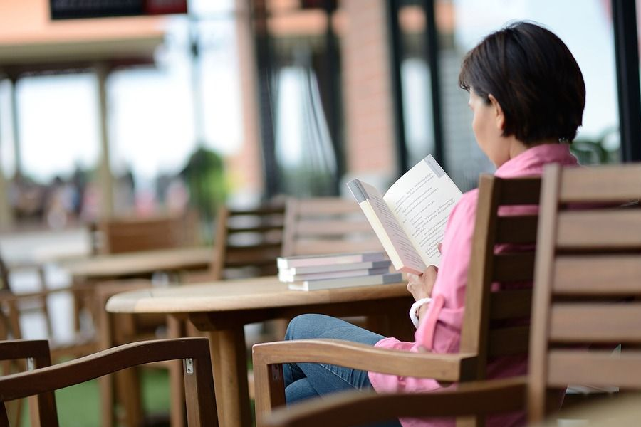 A woman reading a book at an outdoor café, depicting the rising independence and changing roles of women in South Korea.
